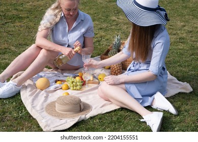 A Two Young Women In A Similar Blue Dress Is Resting On A Picnic, Chees Plate