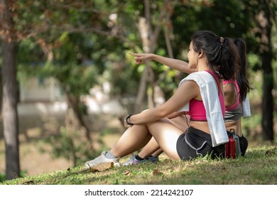 Two Young Women Sitting At The Park And Relaxing After Jogging Outdoors.