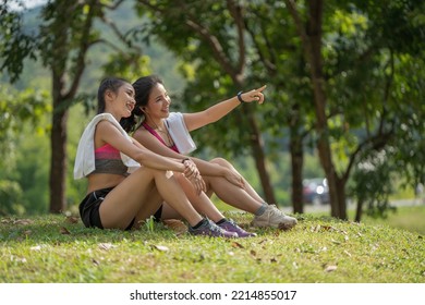 Two Young Women Sitting At The Park And Relaxing After Jogging Outdoors.