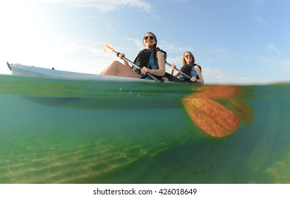 Two Young Women Smiling In Blue Kayak In Atlantic Ocean Off Of The Coast Of Florida