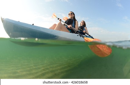 Two Young Women Smiling In Blue Kayak In Atlantic Ocean Off Of The Coast Of Florida