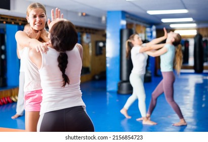 Two young women sparring during self defense course in gym, practicing basic palm strike