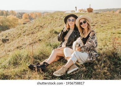 Two Young Women Spend Time Together In Nature. Same Sex Couple Relaxing And Laughing Together With The Dog Outside. High Quality Photo