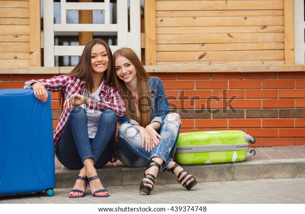 Two young women with
suitcases. Vacation concept. Car trip. Summer vacation. Best friend
posing with their luggage. women traveling with suitcases, walking
on the road