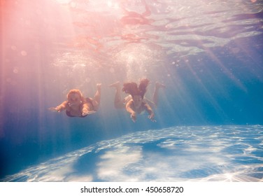 Two Young women swimming underwater in the swimming pool - Powered by Shutterstock