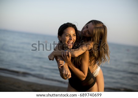 Two young women in swimwear  having fun in the sea at sunset