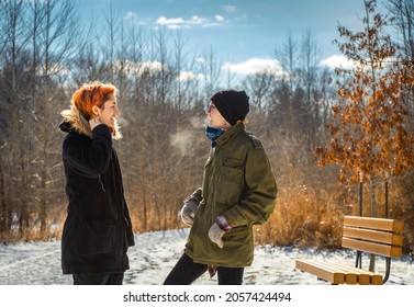 Two Young Women Talking And Laughing On Cold Winter Day In Midwest In Public Park