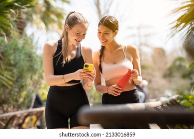 Two young women walking and looking at the phone while playing sports - Shutterstock ID 2133016859