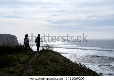 Two young women walking on the cliff overlooking  the ocean