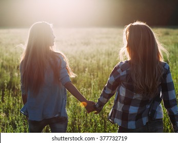 Two Young Women Walking At Sunset.  Back View. Best Friends