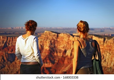 Two young women watching the sunset at the Grand Canyon
