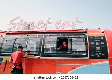 Two young workers in uniform cleaning red food truck in the beginning of working day - Powered by Shutterstock