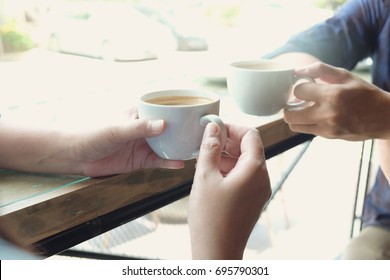 Two younger drinking coffee together, Couple lover having a break drinking coffee in bar ,Close-up shot of hand holding cup of coffee  - Powered by Shutterstock