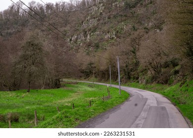 A two-lane turning road without road markings in a rural area near a mountain in France. - Shutterstock ID 2263231531