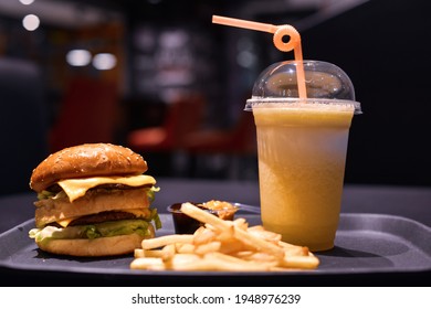 Two-layer hamburger. Ground beef burger, cheese and lettuce with french fries, ketchup sauce, and yellow watermelon juice - Powered by Shutterstock