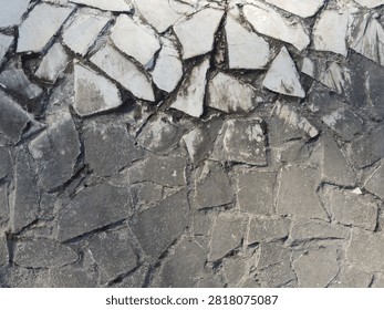 Two-tone cladding made of wild stone. The upper tier is formed from flat fragments of white flagstone with jagged edges, while the massive base is laid with a mosaic of rough gray blocks and mortar.