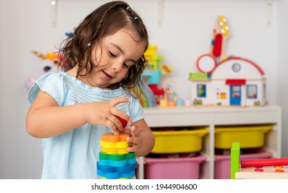 Two-year-old girl, of Caucasian origin, playing and learning very concentrated and smiling with some educational wooden toys in the kindergarten.
