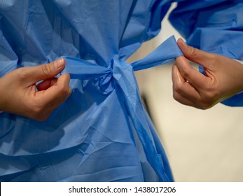 Tying Blue Medical Gown Before A Procedure