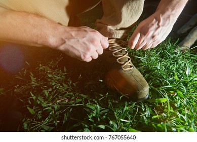 Tying Hiking Shoes Lace Closeup On Green Grass Background. Tourist Tie His Boots