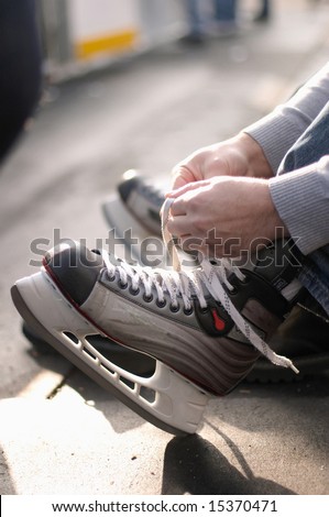 Tying laces of ice hockey skates at skating rink