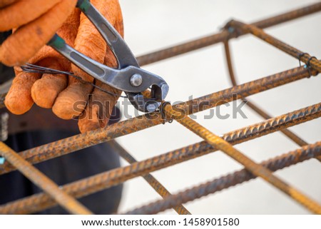 Tying reinforcing steel bars (rebar) for the construction. Tightening wire using a pincers.