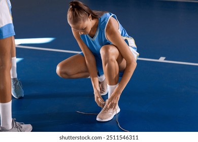 Tying shoelaces, female basketball player preparing for game on court. sports, preparation, athlete, determination, focus, footwear - Powered by Shutterstock