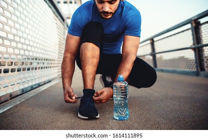Tying sports shoes. Young man getting ready for athletic and fitness training outdoors. Sport, exercise, fitness, workout. Healthy lifestyle - Shutterstock ID 1614111895
