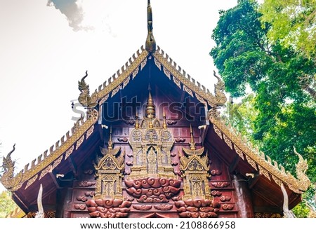 Tympanum of the old chapel, decorated with gold plated,  carved teak wood pattern and culpture  inside the ancient Buddhist temple in the forest
