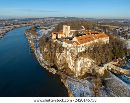 Tyniec near Krakow, Poland. Benedictine abbey, monastery and church on the rocky cliff and Vistula river. Aerial view at sunset in winter with snow and trees