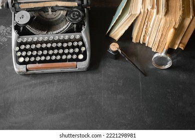 Typewriter, stack of books, magnifying glass, inkwell and ballpen on the black table top view background with copy space. - Shutterstock ID 2221298981