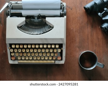 typewriter, tea, binoculars on wooden table - Powered by Shutterstock