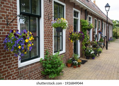 Typical 17th Century Dutch Street View In A Fortified Town With Brick Houses And Front Flower Gardens, Defence Wall, Bridges And Cobblestones Pathways