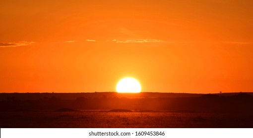 Typical African Sunset With The Sun Being Half Way Behind The Horizon In Front Of A Blood Red Sky In Africa