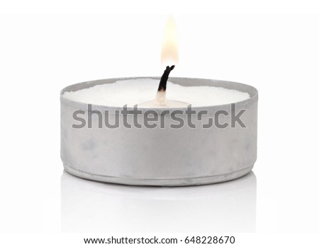 Typical aluminium burning tea candle isolated on white background with shadow reflection. Tea candle with flame and black wick. Tea candle with burning ingle and burned candlewick. Macro photography
