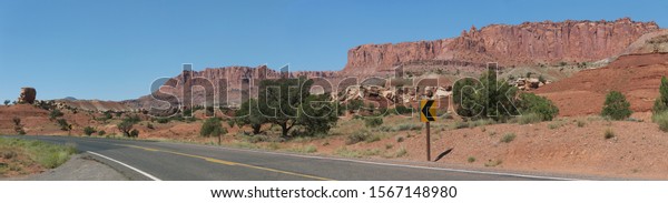 Typical American desert highway\
panorama with red rocks, Utah desert scenic drive with road turn\
sign