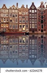 typical amsterdam houses reflected in the canal with blue sky background