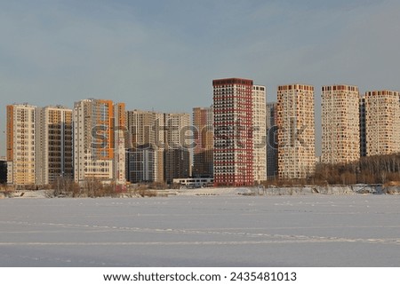 Typical architecture of a Moscow suburb. Snow on a snowy river. Embankment in winter. Sunny winter day. Blue sky