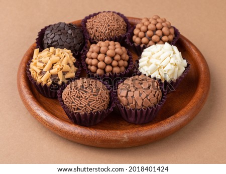 Typical brazilian brigadeiros, various flavors on a wooden plate.