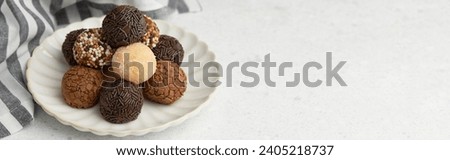Typical Brazilian sweet brigadeiro. A heap of assorted flavors of candies on a white table with copy space