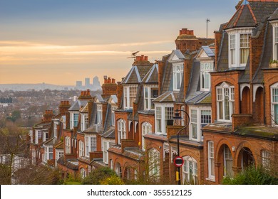 Typical British brick houses on a cloudy morning with sunrise and Canary Wharf at the background. Panoramic shot from Muswell Hill, London, UK