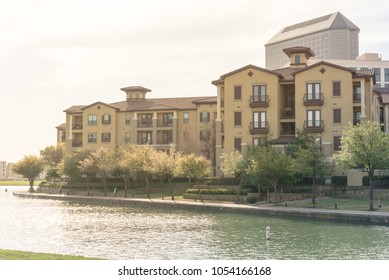 Typical Condo Apartment Homes Overlooking Community Lake With Fountain Spray. Downtown Skyline In Background Las Colinas, Irving, Texas, America.