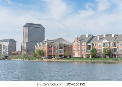 Typical Condo Apartment Homes Overlooking Community Lake With Fountain Spray. Downtown Skyline In Background Las Colinas, Irving, Texas, America.