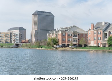 Typical Condo Apartment Homes Overlooking Community Lake With Fountain Spray. Downtown Skyline In Background Las Colinas, Irving, Texas, America.