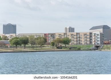 Typical Condo Apartment Homes Overlooking Community Lake With Fountain Spray. Downtown Skyline In Background Las Colinas, Irving, Texas, America.