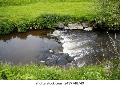 typical Devon countryside and small stream with rocks and grass on the side