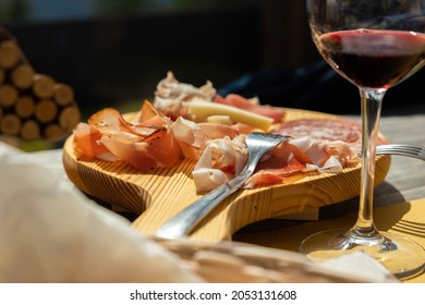 Typical eastern Italy appetizer made of red wine and a cutting board with ham and cheese, close up view, Friuli Venezia Giulia tradition, eating  lunch together concept