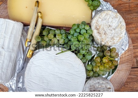 A typical French cheese platter, with a bunch of grapes 