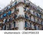 Typical French colonial white 19 th century Renaissance facade of a residential building in Algiers, Alger, Algeria. Clothes drying on balconies. Typical curtains for protection against heat.