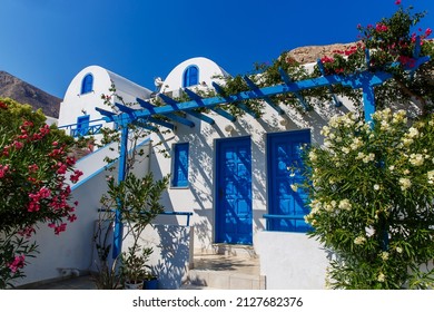 Typical Greek House With Blue Door And Blooming Bougainvillea Plant In Santorini Island Greece