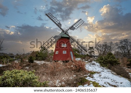 Typical historical red wooden windmill in a winter landscape. Sunset on the coast on a rock. Stenungsund in Sweden